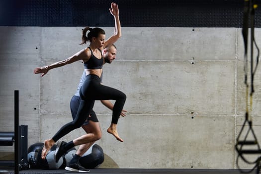 A fit couple exercising various types of jumps in a modern gym, demonstrating their physical fitness, strength, and athletic performance.