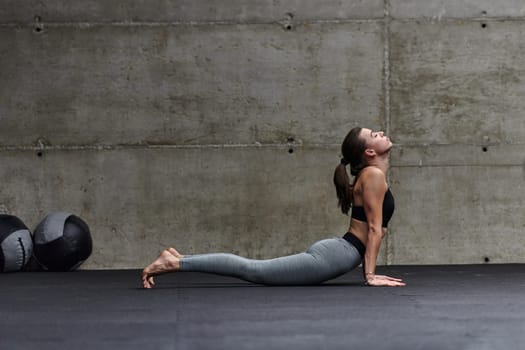 Fit woman in a modern gym working flexibility and strength through various exercises, demonstrating her commitment to fitness.