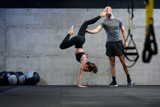 A muscular man assisting a fit woman in a modern gym as they engage in various body exercises and muscle stretches, showcasing their dedication to fitness and benefiting from teamwork and support.