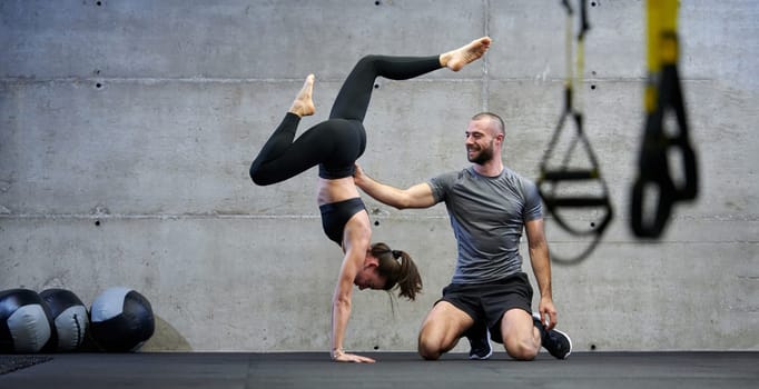 A muscular man assisting a fit woman in a modern gym as they engage in various body exercises and muscle stretches, showcasing their dedication to fitness and benefiting from teamwork and support.