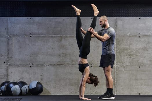 A muscular man assisting a fit woman in a modern gym as they engage in various body exercises and muscle stretches, showcasing their dedication to fitness and benefiting from teamwork and support.