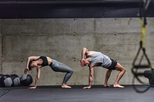 An attractive couple in the gym engaging in various stretching exercises together, showcasing their dedication to fitness, flexibility, and overall wellbeing. With synchronized movements, they demonstrate coordination, balance, and endurance while supporting and motivating each other on their fitness journey.