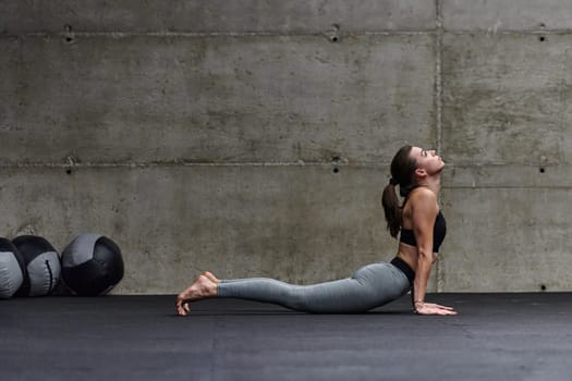 Fit woman in a modern gym working flexibility and strength through various exercises, demonstrating her commitment to fitness.