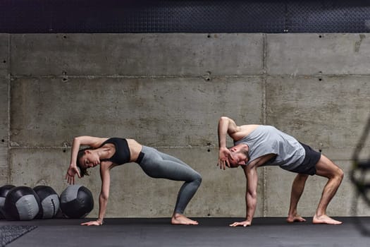 An attractive couple in the gym engaging in various stretching exercises together, showcasing their dedication to fitness, flexibility, and overall wellbeing. With synchronized movements, they demonstrate coordination, balance, and endurance while supporting and motivating each other on their fitness journey.