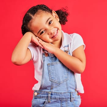 Happy, smile and cute young girl child portrait with red studio background with happiness. Smiling, youth and kid model with denim and adorable hands feeling girly, joyful and positive with fashion.