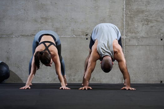 An attractive couple in the gym engaging in various stretching exercises together, showcasing their dedication to fitness, flexibility, and overall wellbeing. With synchronized movements, they demonstrate coordination, balance, and endurance while supporting and motivating each other on their fitness journey.