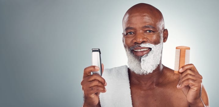 Black man, beard and shaving with razor, cream or comb in cosmetics for skincare, grooming or self care against gray studio background. Portrait of happy African American male and shave kit on mockup.