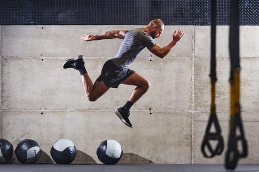 A muscular man captured in air as he jumps in a modern gym, showcasing his athleticism, power, and determination through a highintensity fitness routine.