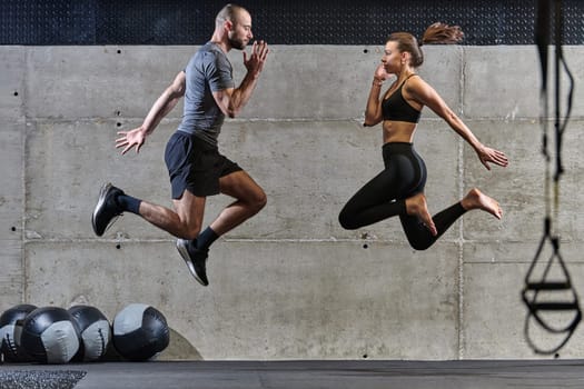 A fit couple exercising various types of jumps in a modern gym, demonstrating their physical fitness, strength, and athletic performance.