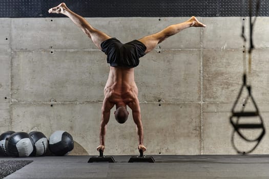 A muscular man in a handstand position, showcasing his exceptional balance and body control while performing a variety of exercises to enhance his overall body stability and strength in a modern gym.