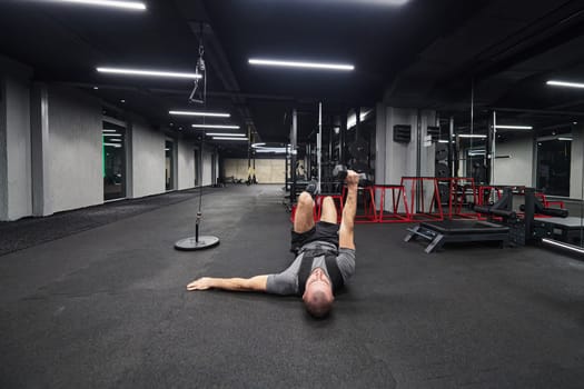 A muscular man is focused on working out with dumbbells in a modern gym, showing his determination and commitment to his fitness regimen