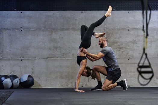 A muscular man assisting a fit woman in a modern gym as they engage in various body exercises and muscle stretches, showcasing their dedication to fitness and benefiting from teamwork and support.