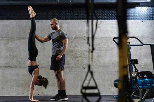 A muscular man assisting a fit woman in a modern gym as they engage in various body exercises and muscle stretches, showcasing their dedication to fitness and benefiting from teamwork and support.