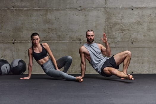 An attractive couple in the gym engaging in various stretching exercises together, showcasing their dedication to fitness, flexibility, and overall wellbeing. With synchronized movements, they demonstrate coordination, balance, and endurance while supporting and motivating each other on their fitness journey.