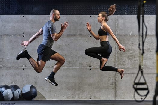 A fit couple exercising various types of jumps in a modern gym, demonstrating their physical fitness, strength, and athletic performance.