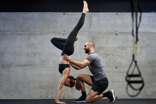 A muscular man assisting a fit woman in a modern gym as they engage in various body exercises and muscle stretches, showcasing their dedication to fitness and benefiting from teamwork and support.