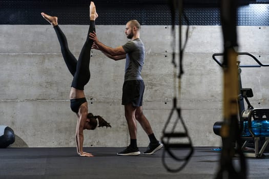 A muscular man assisting a fit woman in a modern gym as they engage in various body exercises and muscle stretches, showcasing their dedication to fitness and benefiting from teamwork and support.