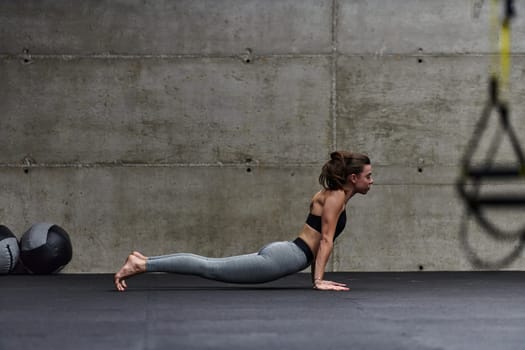 Fit woman in a modern gym working flexibility and strength through various exercises, demonstrating her commitment to fitness.