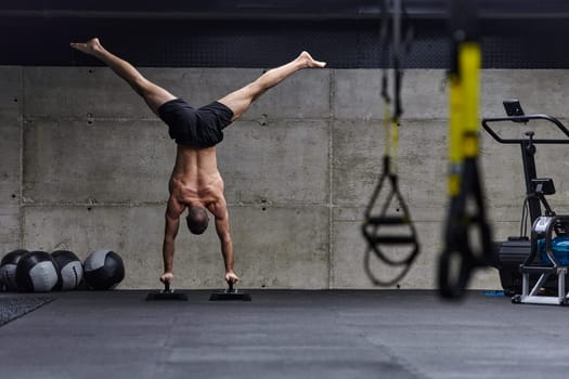 A muscular man in a handstand position, showcasing his exceptional balance and body control while performing a variety of exercises to enhance his overall body stability and strength in a modern gym.