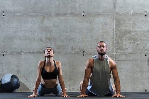 An attractive couple in the gym engaging in various stretching exercises together, showcasing their dedication to fitness, flexibility, and overall wellbeing. With synchronized movements, they demonstrate coordination, balance, and endurance while supporting and motivating each other on their fitness journey.