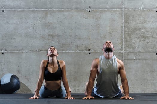 An attractive couple in the gym engaging in various stretching exercises together, showcasing their dedication to fitness, flexibility, and overall wellbeing. With synchronized movements, they demonstrate coordination, balance, and endurance while supporting and motivating each other on their fitness journey.