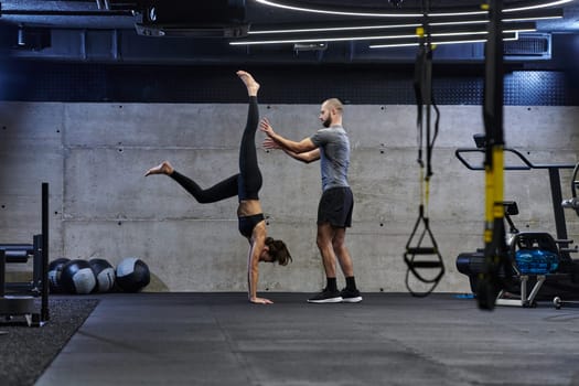 A muscular man assisting a fit woman in a modern gym as they engage in various body exercises and muscle stretches, showcasing their dedication to fitness and benefiting from teamwork and support.