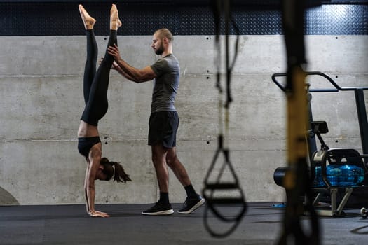 A muscular man assisting a fit woman in a modern gym as they engage in various body exercises and muscle stretches, showcasing their dedication to fitness and benefiting from teamwork and support.