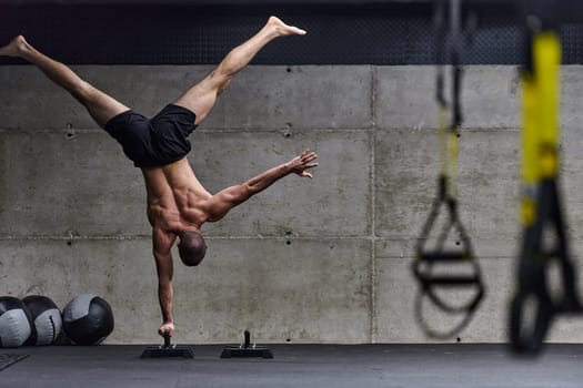 A muscular man in a handstand position, showcasing his exceptional balance and body control while performing a variety of exercises to enhance his overall body stability and strength in a modern gym.