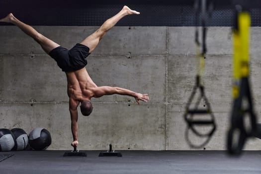 A muscular man in a handstand position, showcasing his exceptional balance and body control while performing a variety of exercises to enhance his overall body stability and strength in a modern gym.