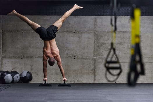 A muscular man in a handstand position, showcasing his exceptional balance and body control while performing a variety of exercises to enhance his overall body stability and strength in a modern gym.