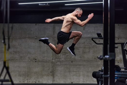 A muscular man captured in air as he jumps in a modern gym, showcasing his athleticism, power, and determination through a highintensity fitness routine.