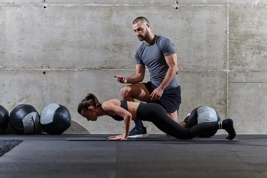 A muscular man assisting a fit woman in a modern gym as they engage in various body exercises and muscle stretches, showcasing their dedication to fitness and benefiting from teamwork and support.