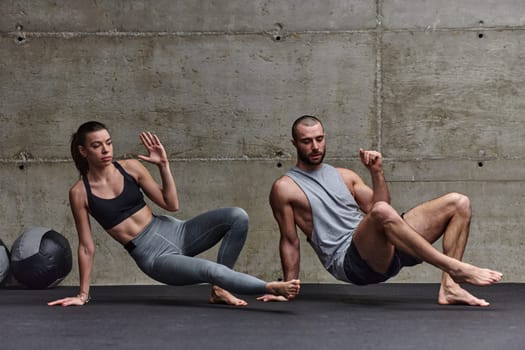 An attractive couple in the gym engaging in various stretching exercises together, showcasing their dedication to fitness, flexibility, and overall wellbeing. With synchronized movements, they demonstrate coordination, balance, and endurance while supporting and motivating each other on their fitness journey.