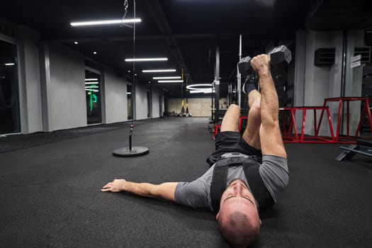 A muscular man is focused on working out with dumbbells in a modern gym, showing his determination and commitment to his fitness regimen