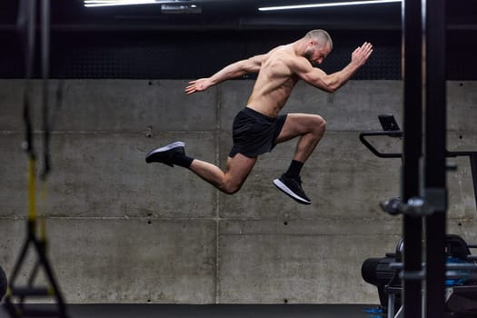 A muscular man captured in air as he jumps in a modern gym, showcasing his athleticism, power, and determination through a highintensity fitness routine.