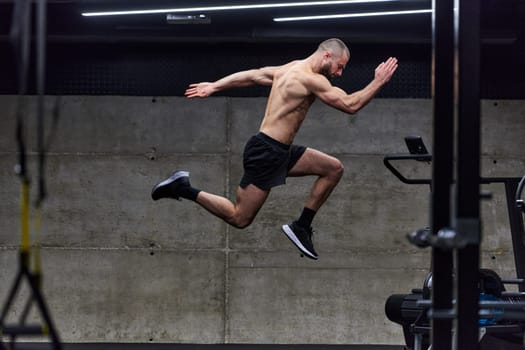 A muscular man captured in air as he jumps in a modern gym, showcasing his athleticism, power, and determination through a highintensity fitness routine.