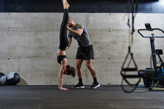 A muscular man assisting a fit woman in a modern gym as they engage in various body exercises and muscle stretches, showcasing their dedication to fitness and benefiting from teamwork and support.