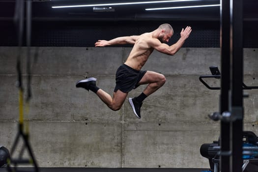 A muscular man captured in air as he jumps in a modern gym, showcasing his athleticism, power, and determination through a highintensity fitness routine.