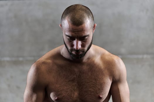 A muscular man poses in the gym, showcasing his strength and dedication to fitness through an impressive physique and glistening sweat on his face