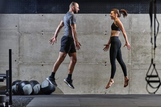 A fit couple exercising various types of jumps in a modern gym, demonstrating their physical fitness, strength, and athletic performance.