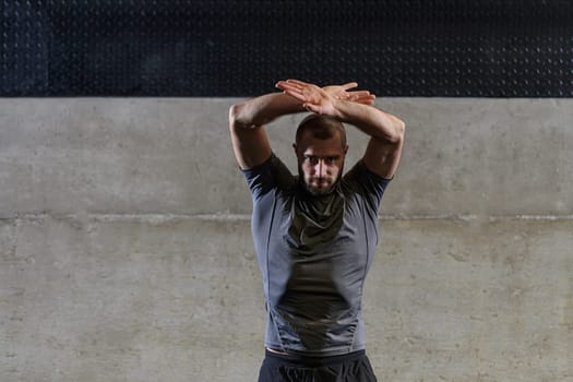 A muscular man working stretching exercises for his arms and body muscles in modern gym .