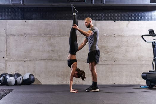 A muscular man assisting a fit woman in a modern gym as they engage in various body exercises and muscle stretches, showcasing their dedication to fitness and benefiting from teamwork and support.