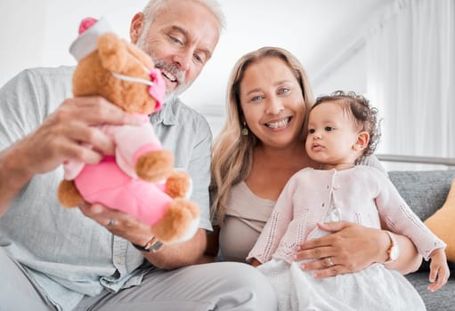 Mature, couple and baby with a toy while babysitting grand daughter with love, care and affection for fun playing. Caring, living room and grandfather, grandmother and child bonding with teddybear.