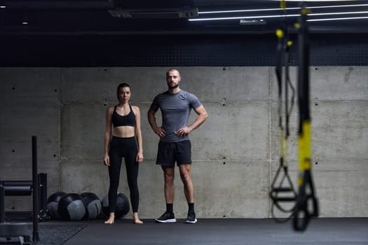 Muscular man and fit woman in a conversation before commencing their training session in a modern gym