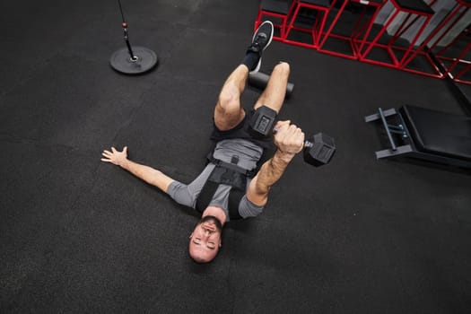 A muscular man is focused on working out with dumbbells in a modern gym, showing his determination and commitment to his fitness regimen