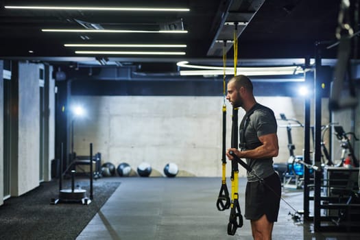 A muscular man in the gym, preparing for his workout, exudes determination and focus as he gets ready to push his limits and achieve his fitness goals