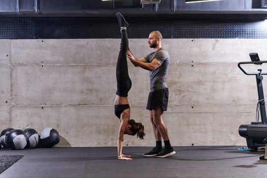 A muscular man assisting a fit woman in a modern gym as they engage in various body exercises and muscle stretches, showcasing their dedication to fitness and benefiting from teamwork and support.