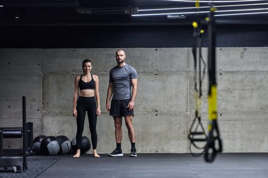 Muscular man and fit woman in a conversation before commencing their training session in a modern gym