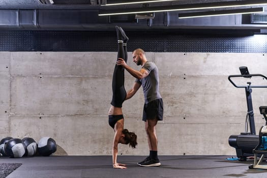 A muscular man assisting a fit woman in a modern gym as they engage in various body exercises and muscle stretches, showcasing their dedication to fitness and benefiting from teamwork and support.