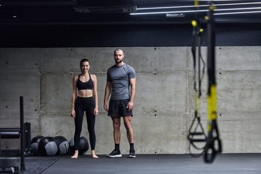 Muscular man and fit woman in a conversation before commencing their training session in a modern gym